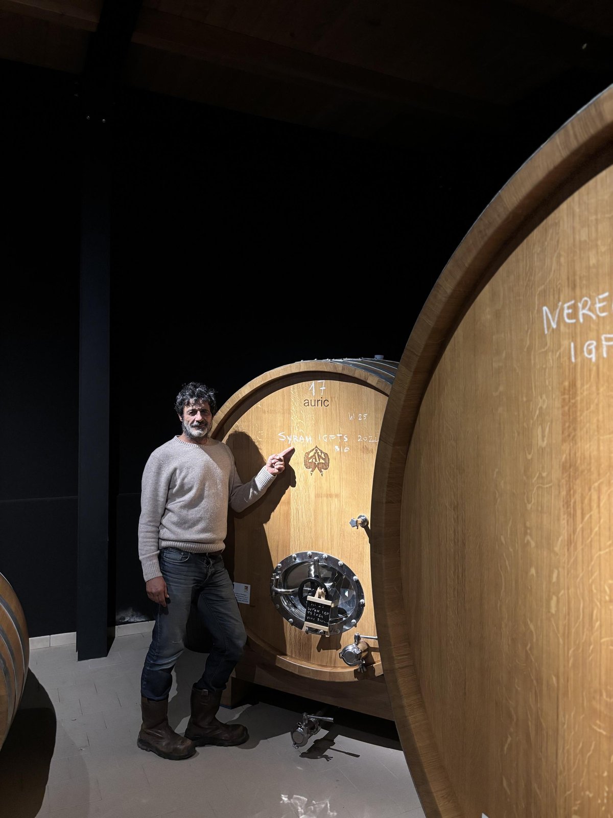Winemaker Aldo Viola pointing to a wooden foudre containing Syrah.